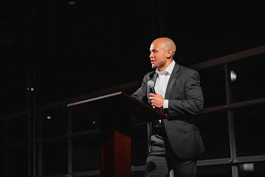PJ speaking at a podium during a university event